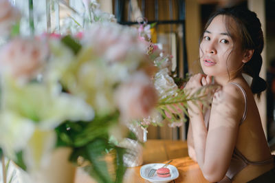 Portrait of young woman sitting on plant