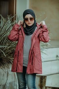 Woman wearing sunglasses standing against wall