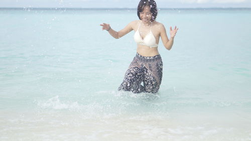 Full length of shirtless man standing in sea