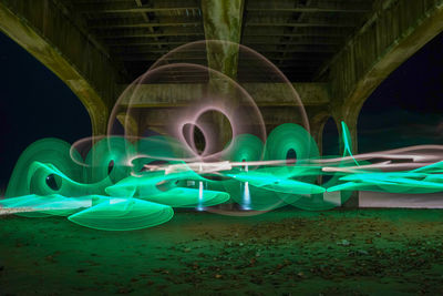 Light trails over illuminated bridge at night