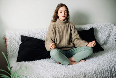 Young woman sitting on bed at home