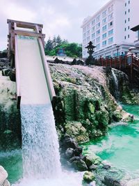 Fountain by sea against buildings