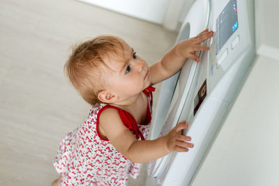 Side view of cute baby girl standing against wall