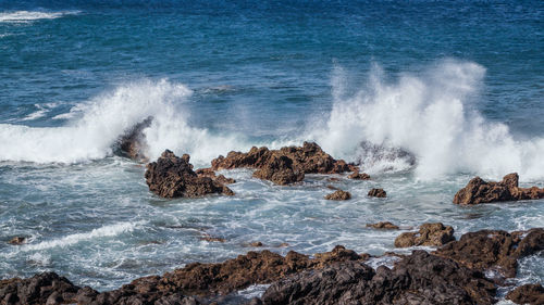 High angle view of waves splashing and crashing  on and over rocks white water surf 