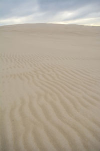 Sand dunes in desert against sky