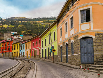 Road by buildings against sky in city