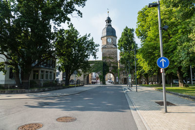 Street amidst trees and buildings against sky