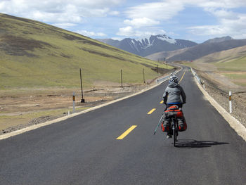 Rear view of man riding bicycle on road