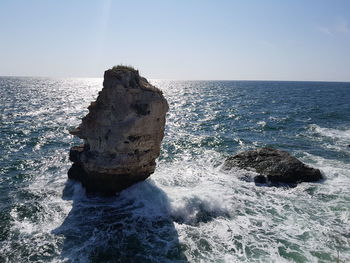 Rock formation in sea against sky