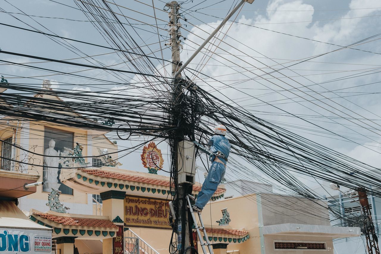 LOW ANGLE VIEW OF CABLES AGAINST BUILDINGS