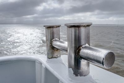 Close-up of machine part by sea against sky