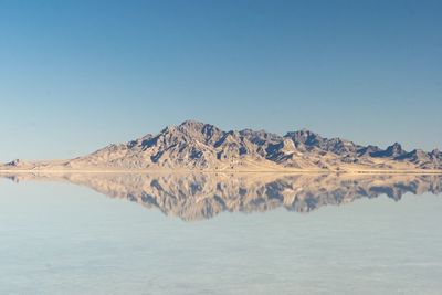 Scenic view of lake and mountains against clear blue sky