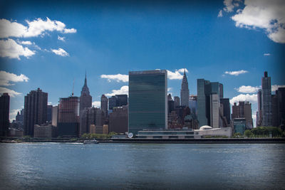 City at waterfront against cloudy sky