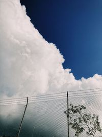 Low angle view of fence against cloudy sky