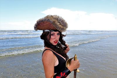 Portrait of young woman at beach against sky