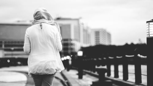 Rear view of woman standing against buildings in city