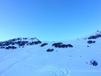 Scenic view of snow covered mountains against clear blue sky