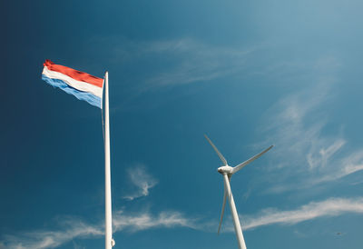 Low angle view of windmill and dutch flag against sky