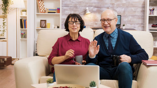 Senior couple talking on video call on sofa at home