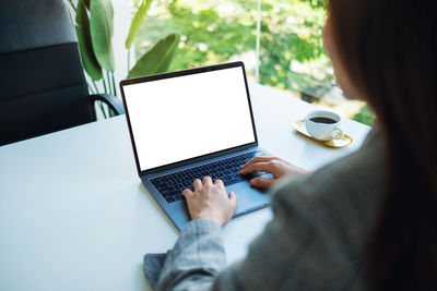 Mockup image of a woman using and typing on laptop keyboard with blank white desktop screen