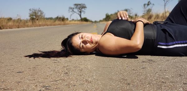 Portrait of woman lying on road