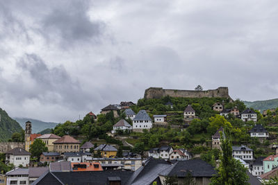 Buildings in town against cloudy sky