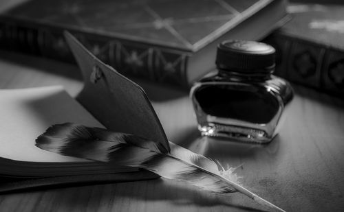 Close-up of ink and quill pen with diary on table