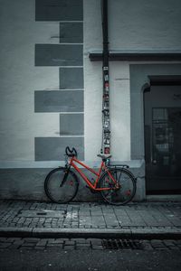 Bicycle parked on footpath against building
