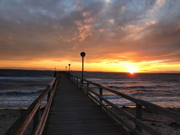 Pier over sea against sky during sunset