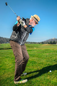 Full length of senior man playing golf against clear sky