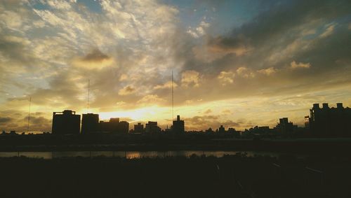 Silhouette of building against cloudy sky at sunset