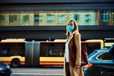 Woman in protective mask walks at city street