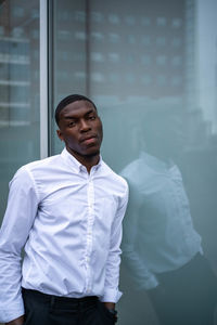 Portrait of young man standing against window
