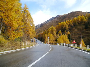 Road amidst trees against sky during autumn