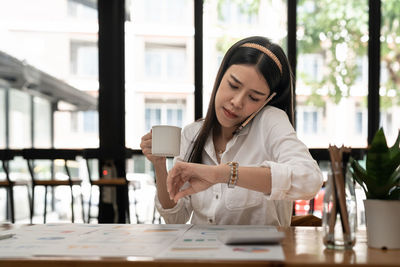 Young woman using mobile phone while sitting on table