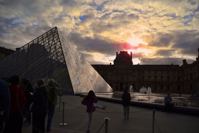 People in city against cloudy sky
