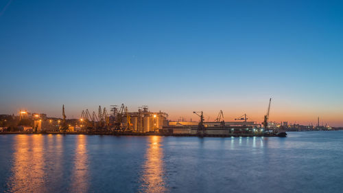 Commercial dock by sea against clear sky during sunset