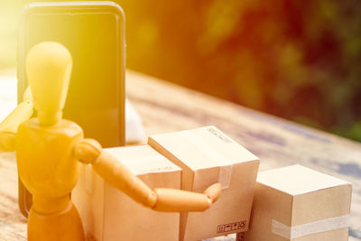 Close-up of figurine with cardboard boxes and mobile phone on table
