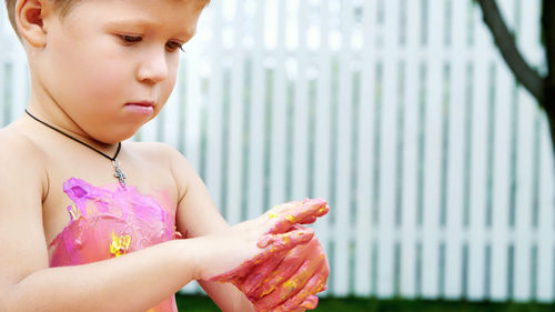 A little child, a four-year-old boy playing, painting with finger paints, decorating himself, in