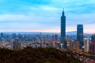 Aerial view of buildings in city against cloudy sky