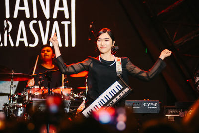 Woman with arms raised in music concert