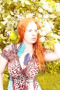 Portrait of young woman standing against tree