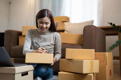 Young businesswoman writing on box