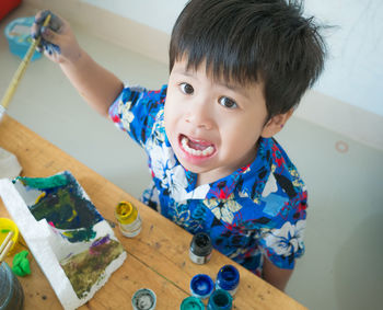 High angle view of cute boy painting on table at home