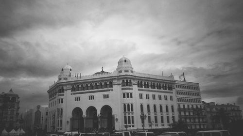Buildings in city against cloudy sky