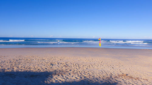 Scenic view of beach against clear blue sky