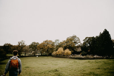 Rear view of woman walking on field against clear sky