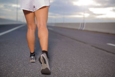 Female sport runner getting ready for jogging outdoors on  the city road.