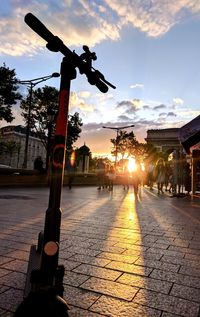 Street lights on footpath in city at sunset