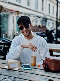 Portrait of smiling young man sitting at cafe in city